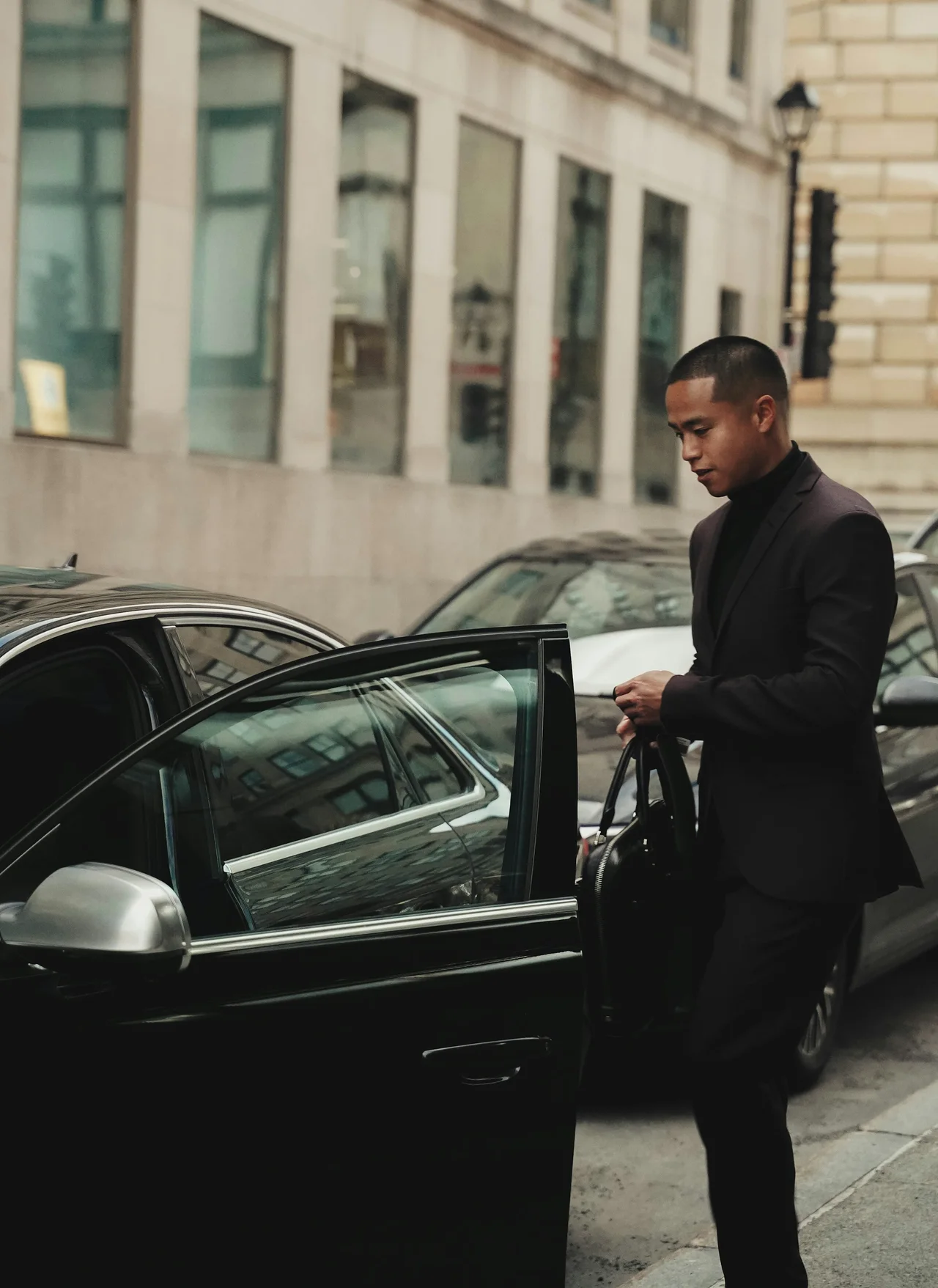 Chauffeur standing beside a black sedan